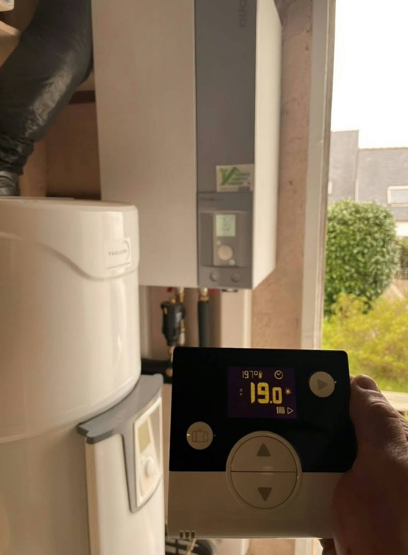 Technicien réglant un thermostat à côté d’un ballon thermodynamique